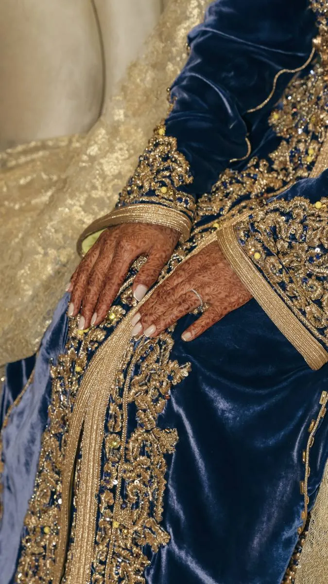 Détail des mains ornées de henné sur une tenue traditionnelle bleue et or