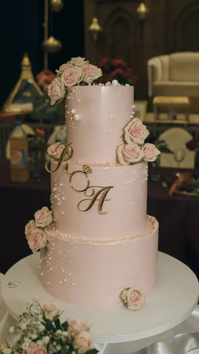 Pièce montée à trois étages ornée de roses et des initiales des mariés