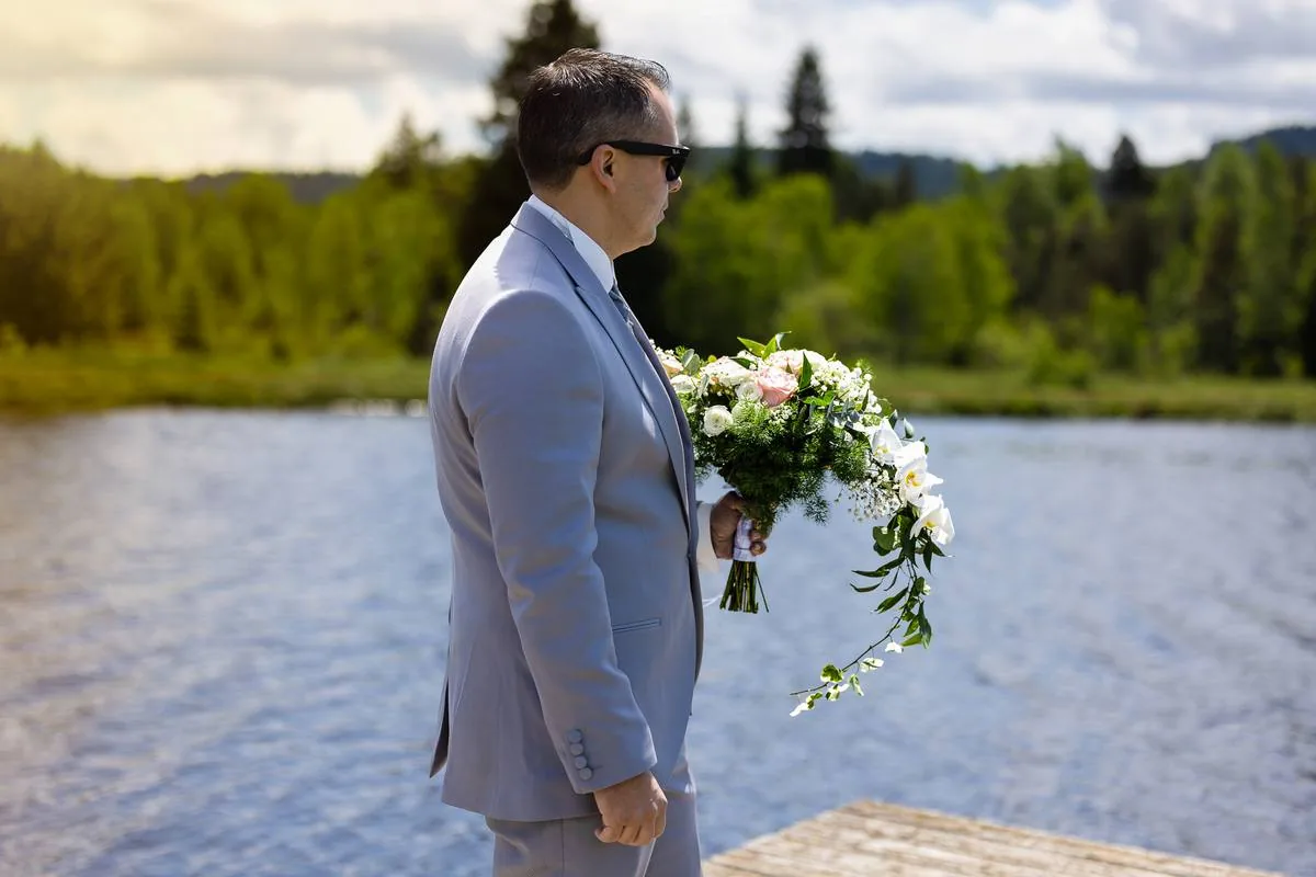Marié tenant le bouquet au bord d'un lac