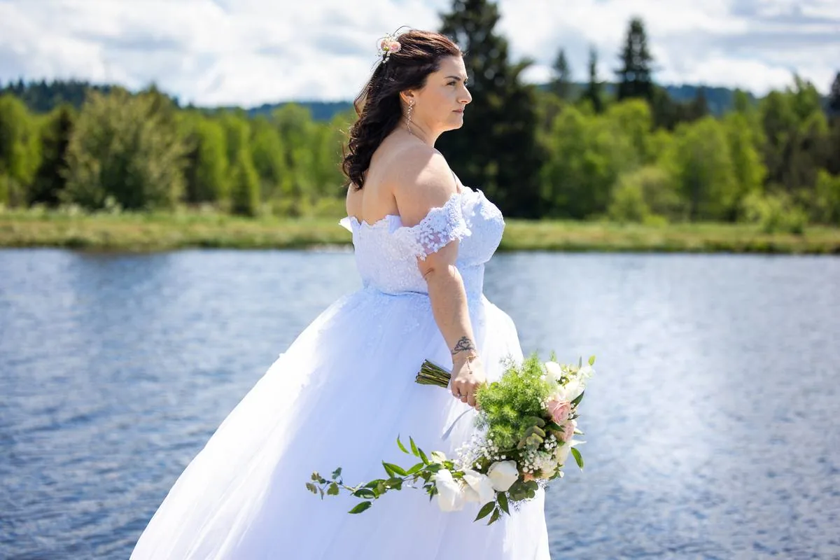 Mariée en robe blanche posant au bord d'un lac