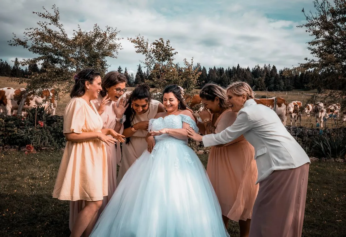 Demoiselles d'honneur ajustant la robe de la mariée